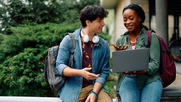 Two students talking over a laptop